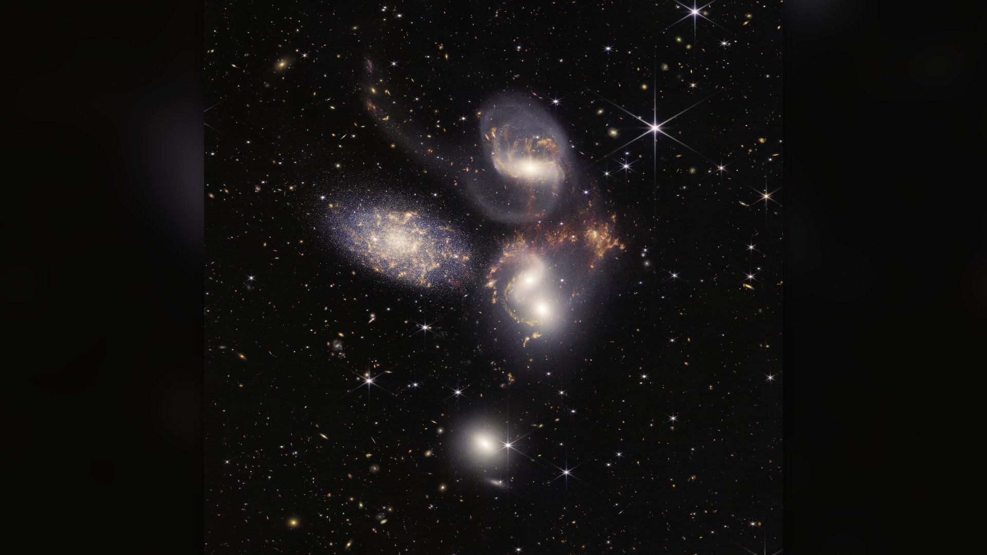 James Webb Space Telescope infrared mosaic of Stephan's Quintet, showing five closely grouped galaxies with glowing shockwaves and sweeping gas tails.