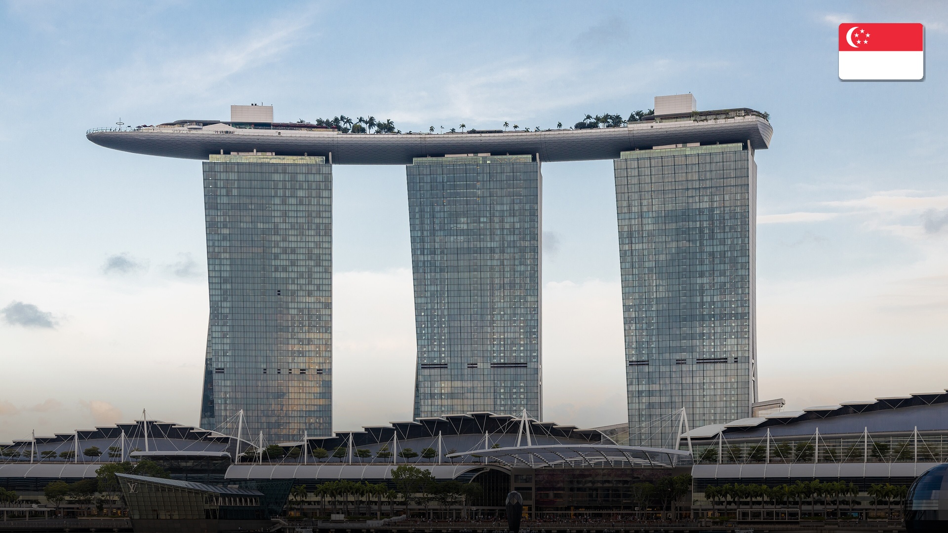 Marina Bay Sands hotel and waterfront promenade illuminated against the evening Singapore skyline.