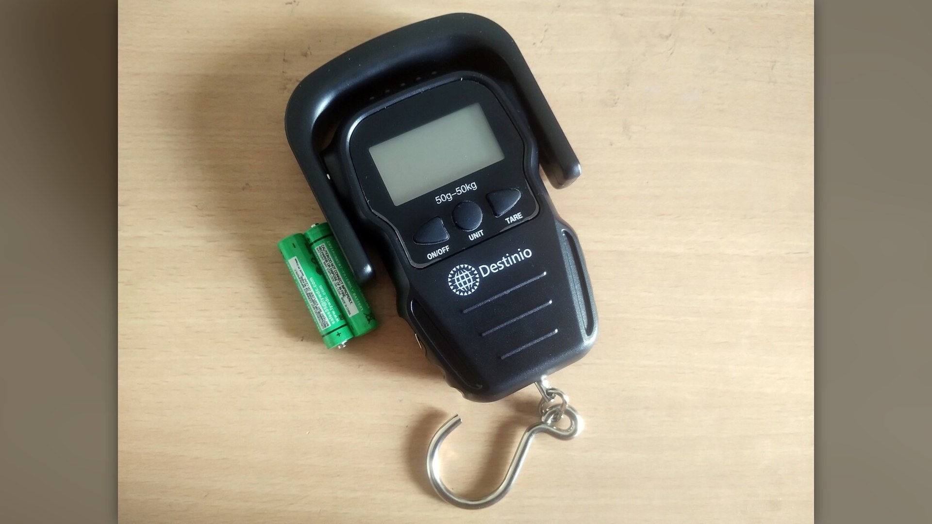 A handheld digital hanging luggage scale measuring suitcase weight.