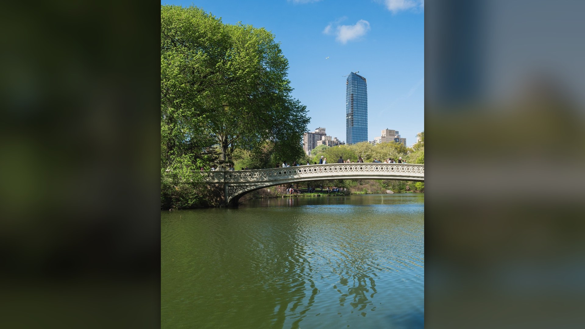 Bow Bridge and autumn foliage in Central Park with the Manhattan skyline in New York City.