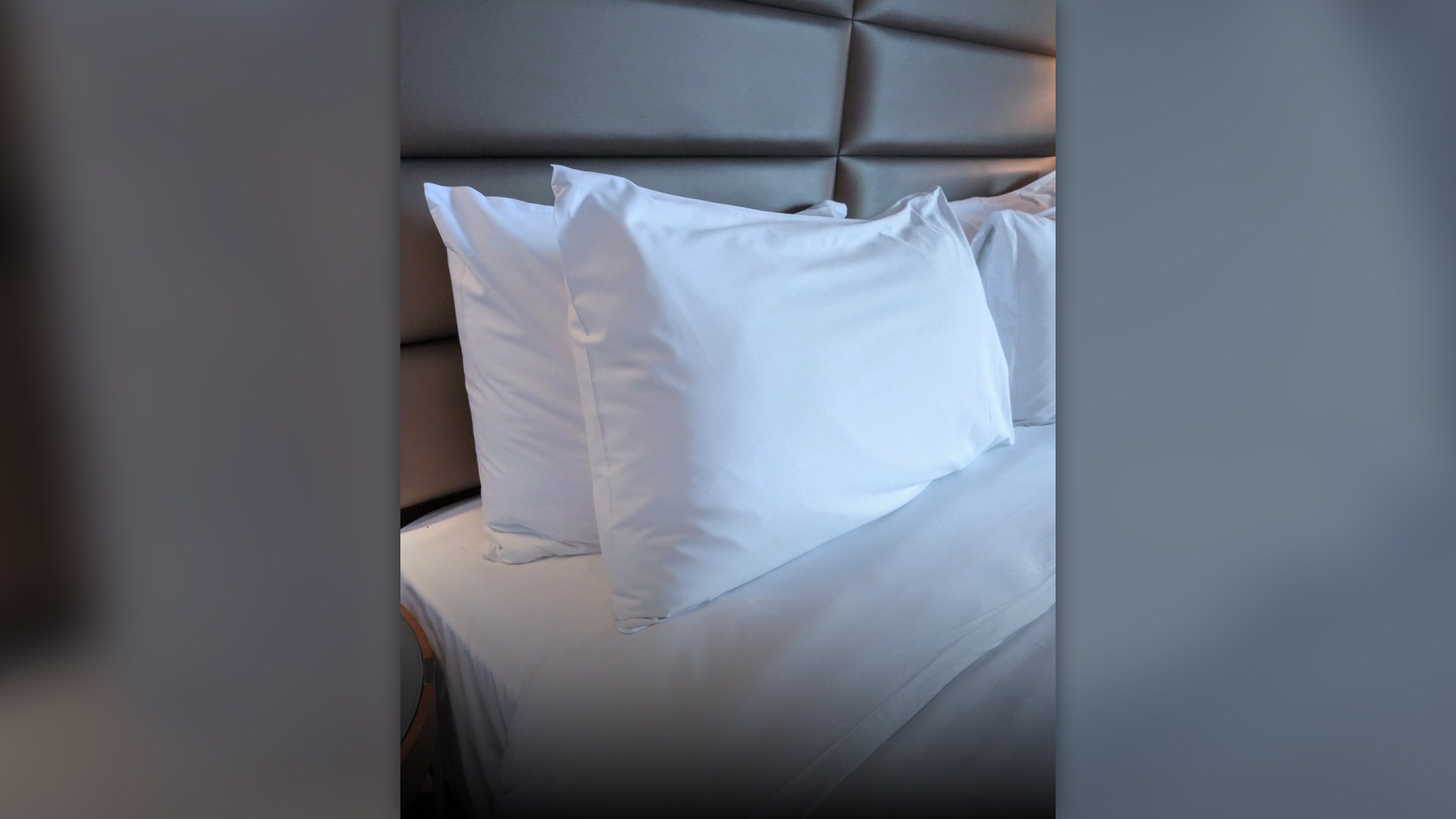 White bed pillows in cotton pillowcases arranged on a mattress.