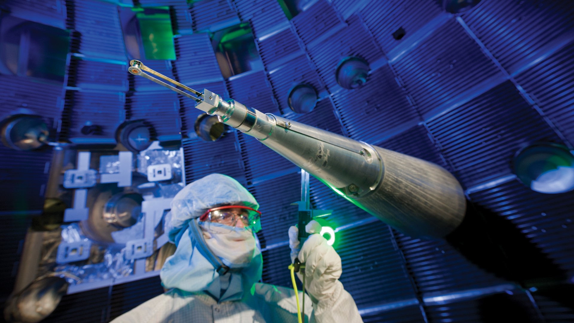 Worker in protective suit inspecting the interior of the National Ignition Facility target chamber.