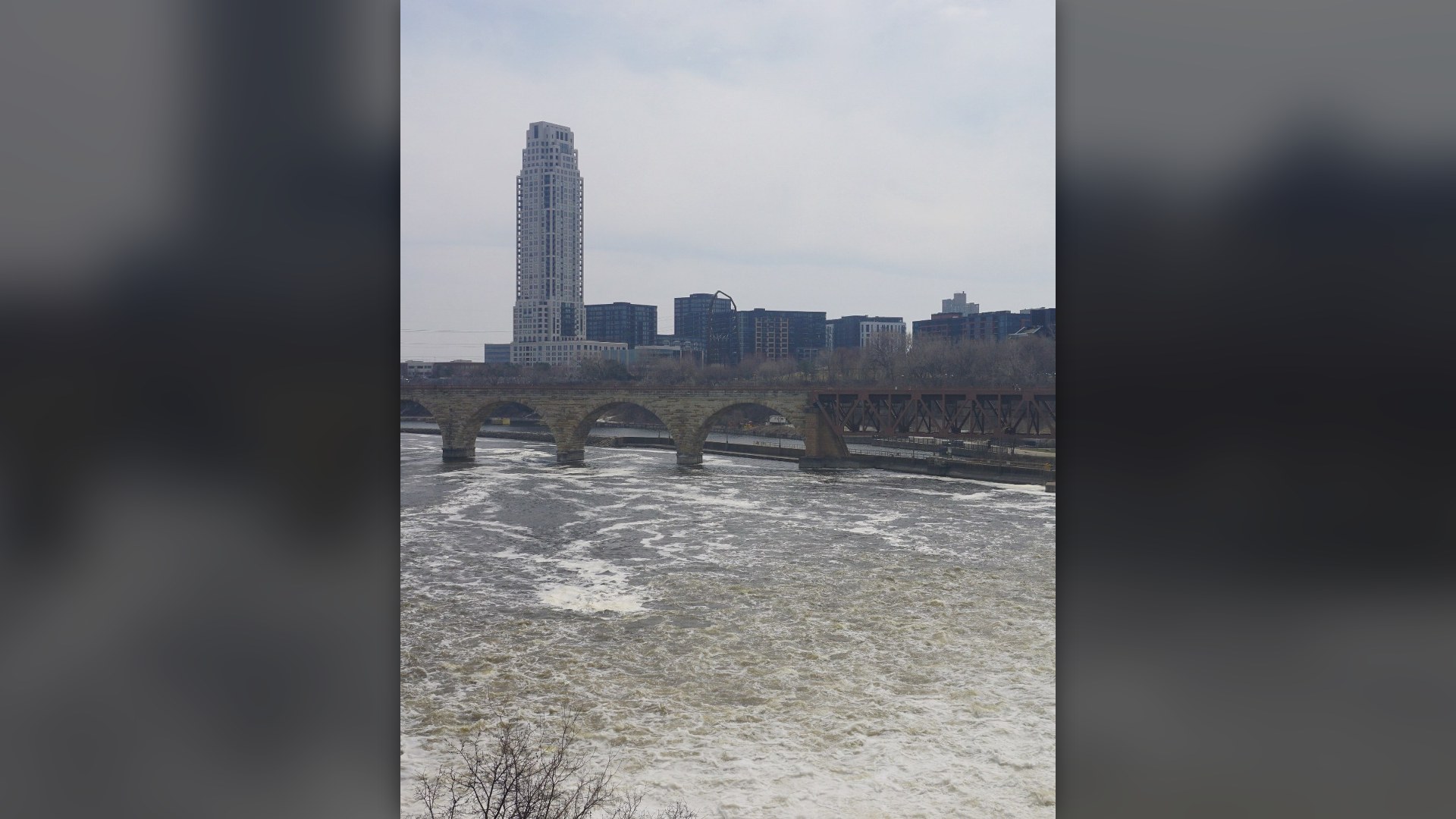 Historic Stone Arch Bridge spanning the Mississippi River in front of the Minneapolis, Minnesota skyline.