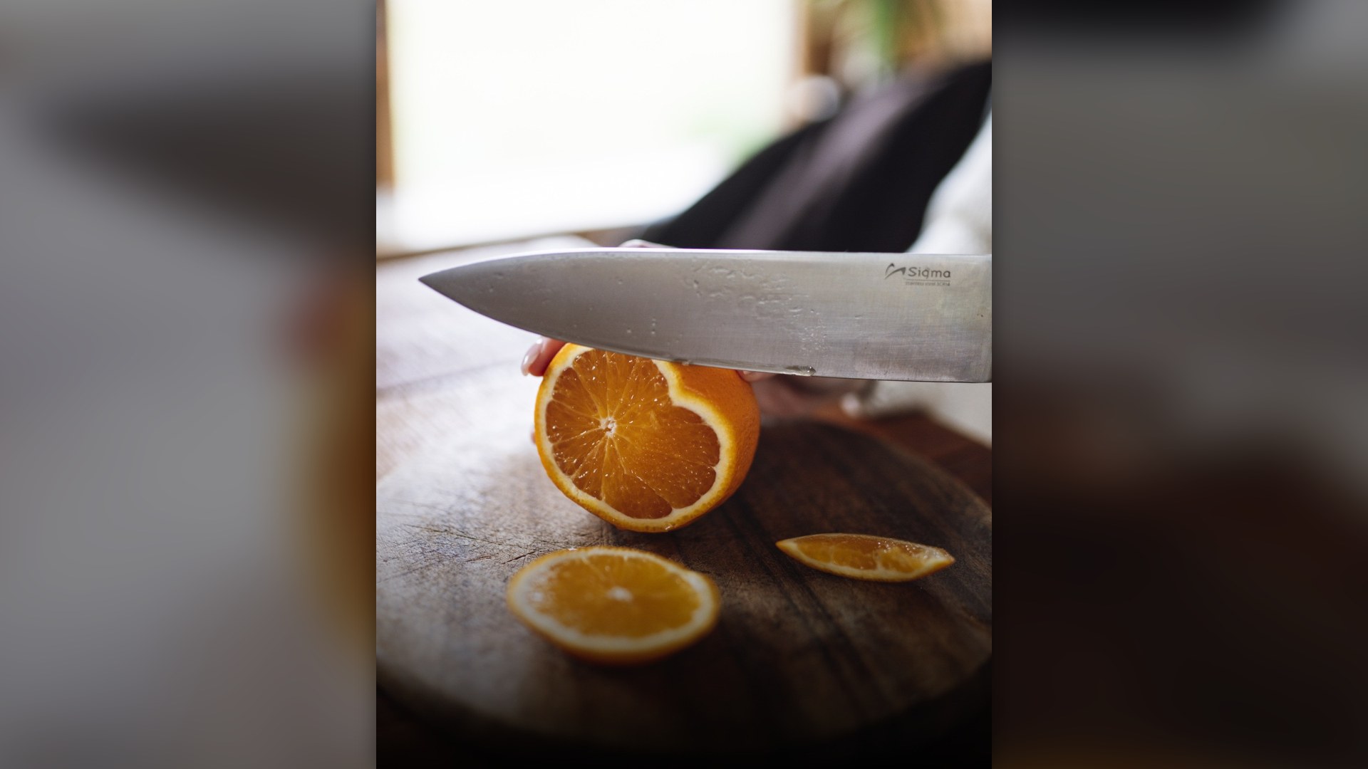 Wooden cutting board in a kitchen with a knife slicing food.