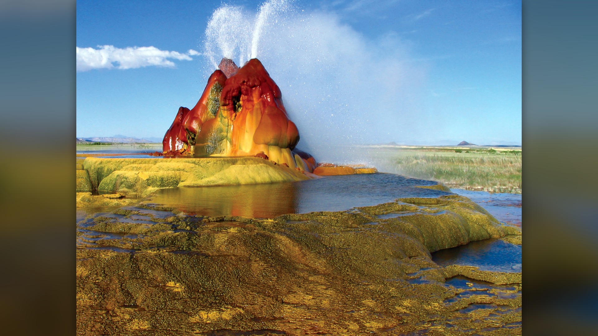 Steaming hot water spraying from the red and green mineral cones of Fly Geyser in Nevada.