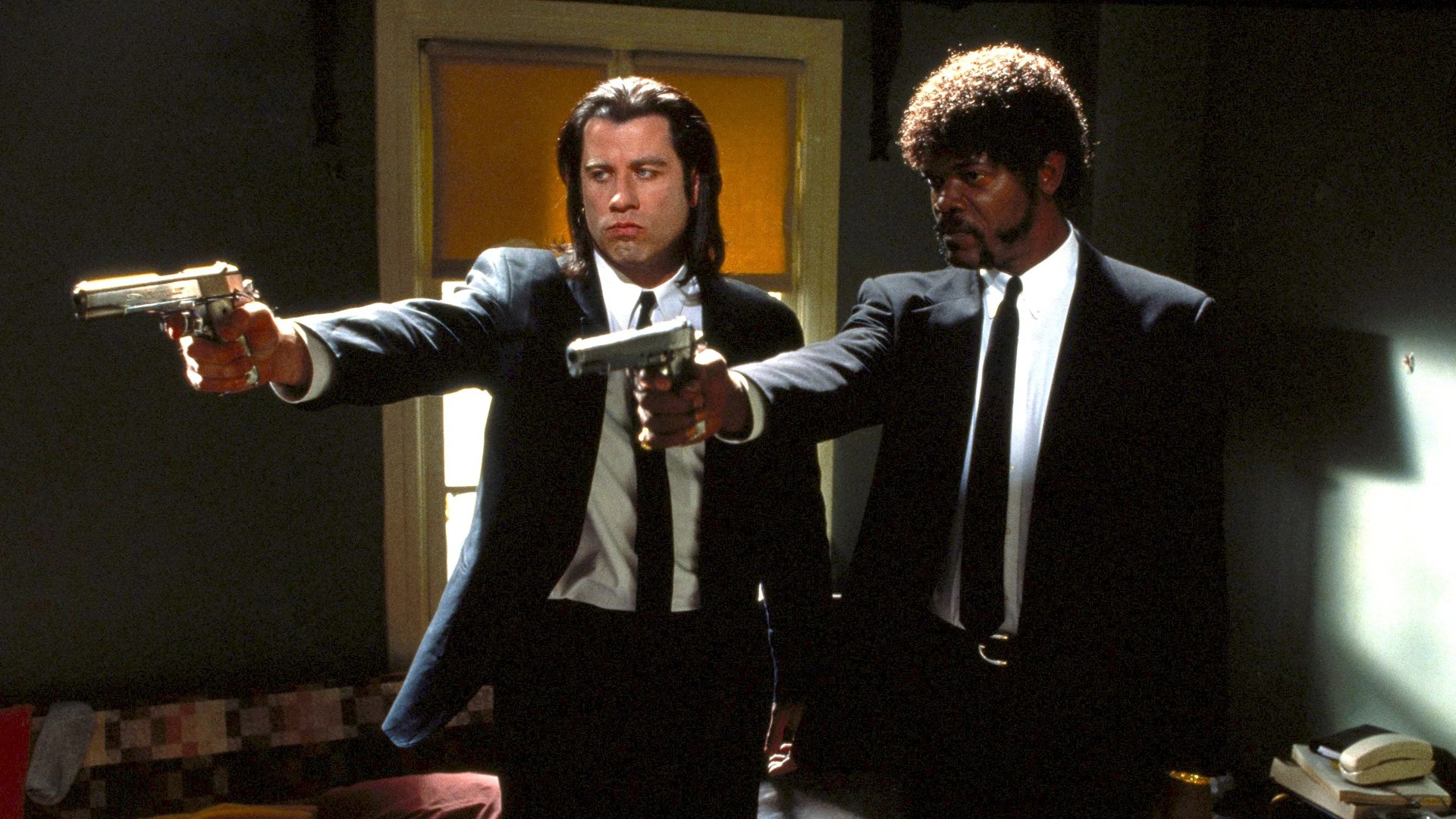 Vincent Vega and Jules Winnfield point their pistols in matching black suits in Pulp Fiction.