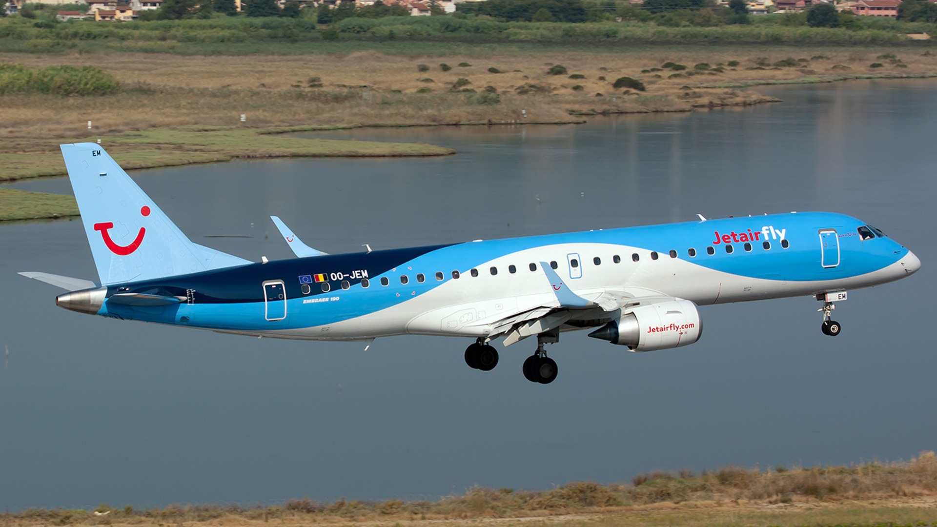 Jetairfly Embraer 190 landing over the lagoon at Corfu International Airport in Greece.