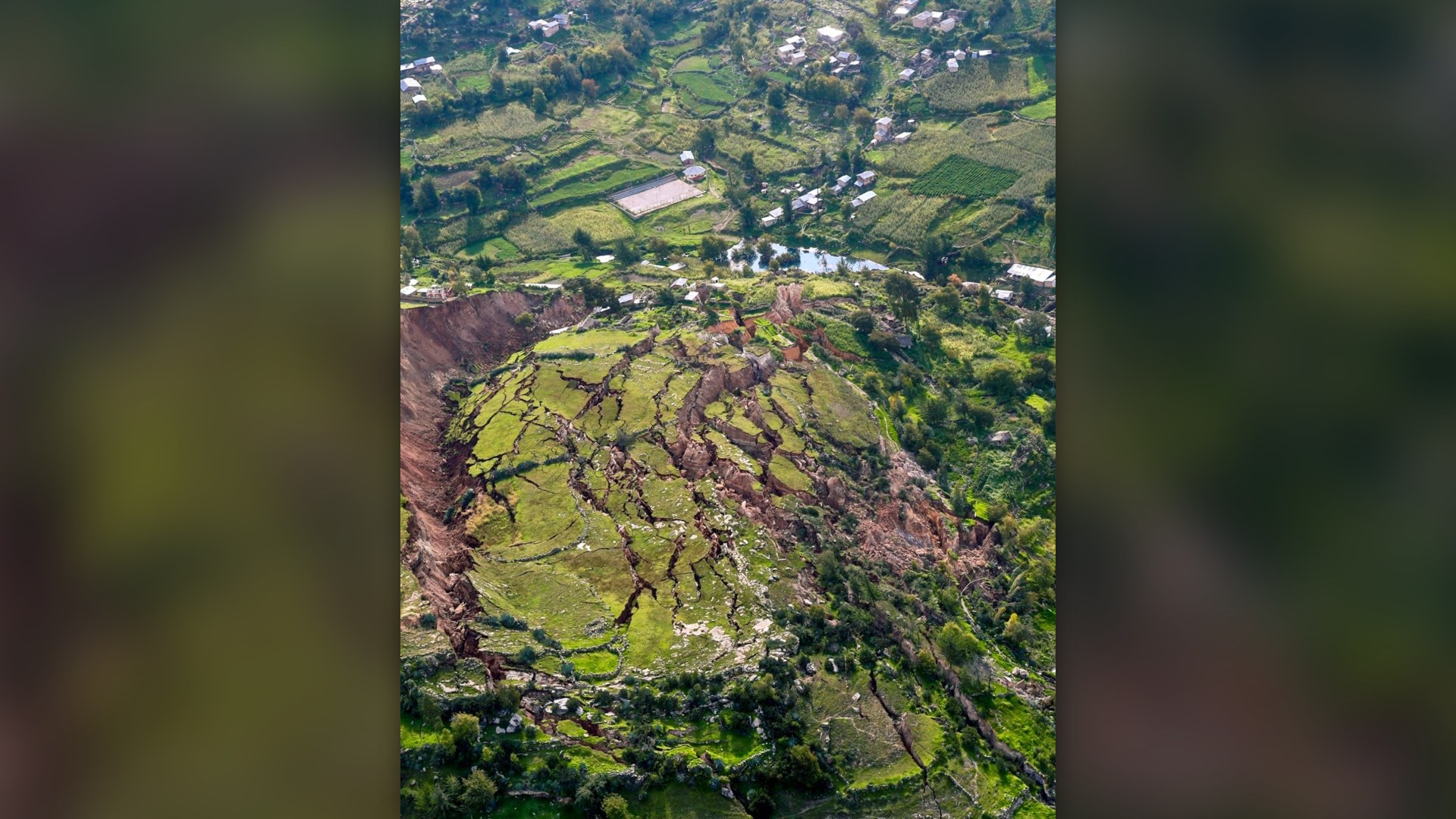 Aerial view of a massive mountainside landslide fracturing and collapsing into an Andean valley in Peru.