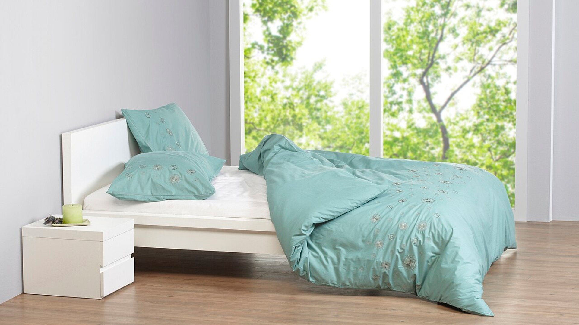 Tightly made bed with tucked sheets at the foot of the mattress