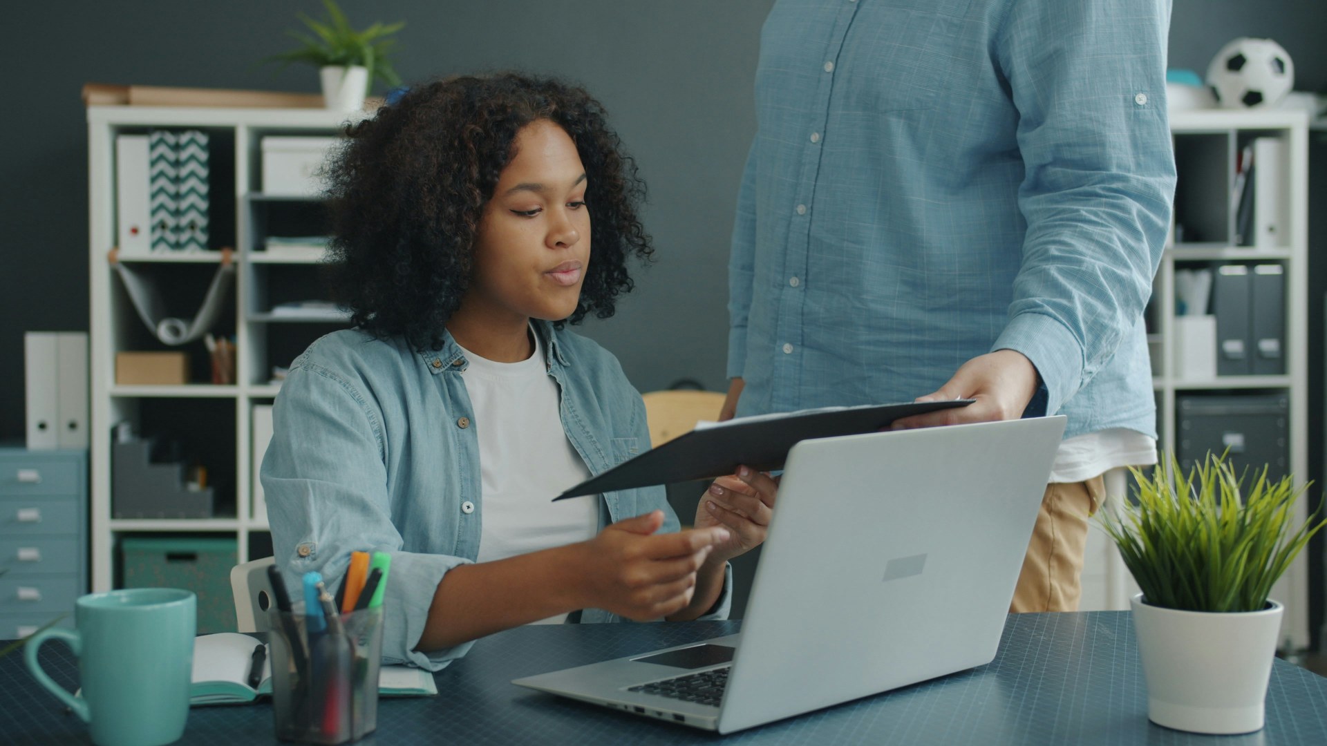 Two office colleagues comparing compensation documents at a corporate desk.