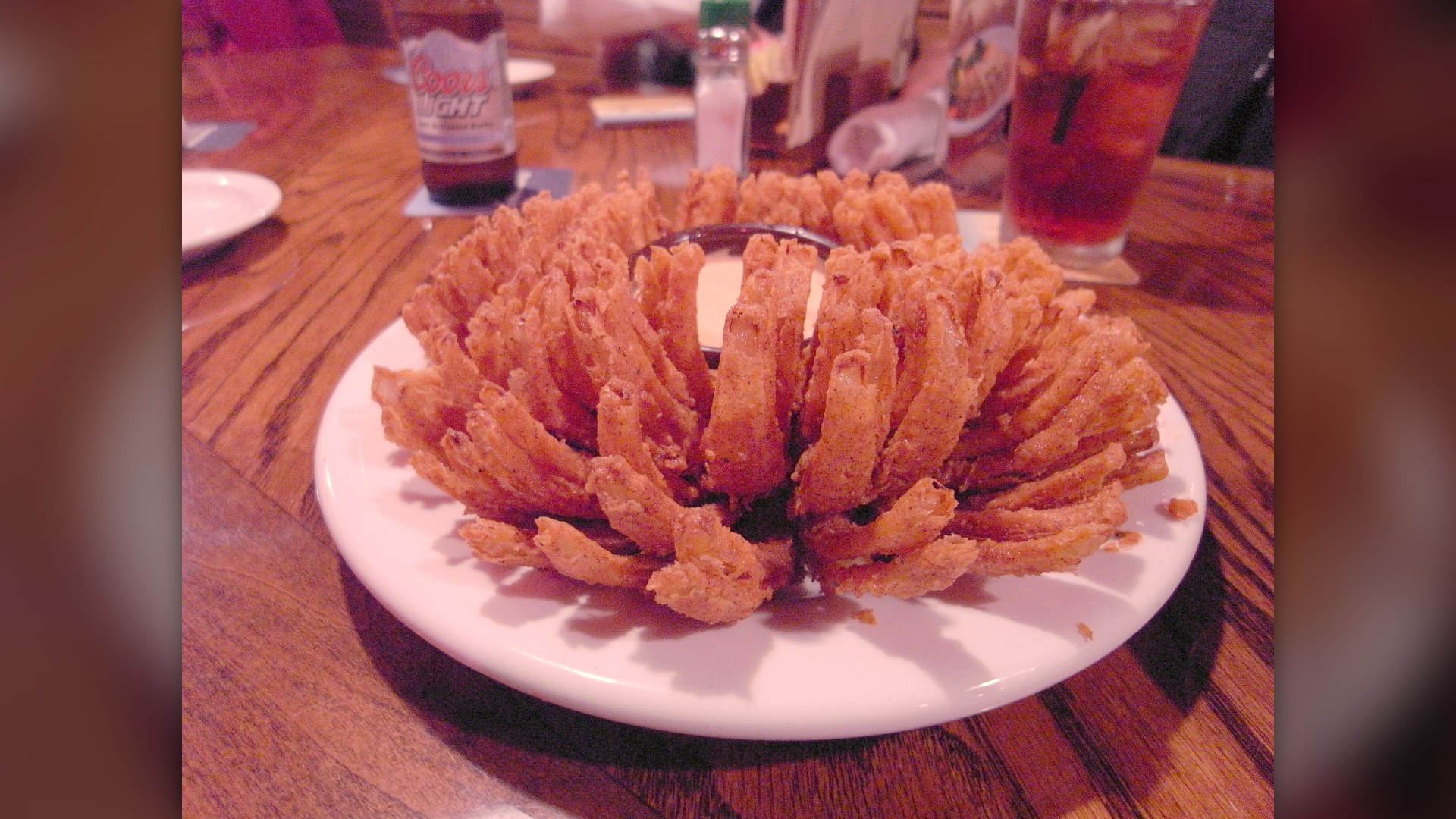 A battered and deep-fried Bloomin' Onion appetizer served with dipping sauce.
