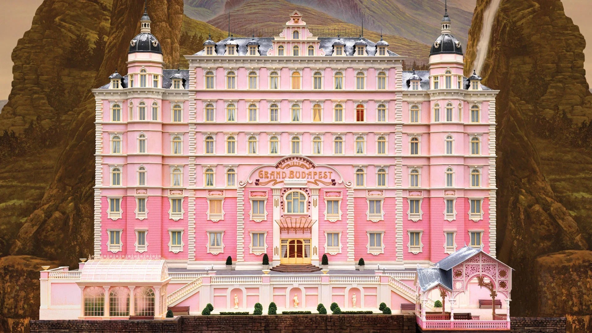 The pastel pink facade of the Grand Budapest Hotel nestled in the alpine mountains of Zubrowka.