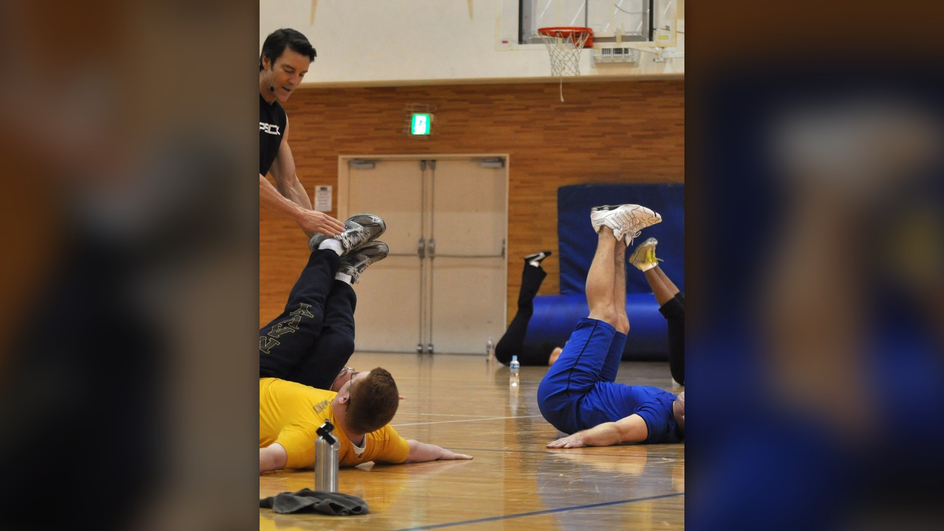 Fitness coach instructing naval personnel on proper abdominal exercise execution.