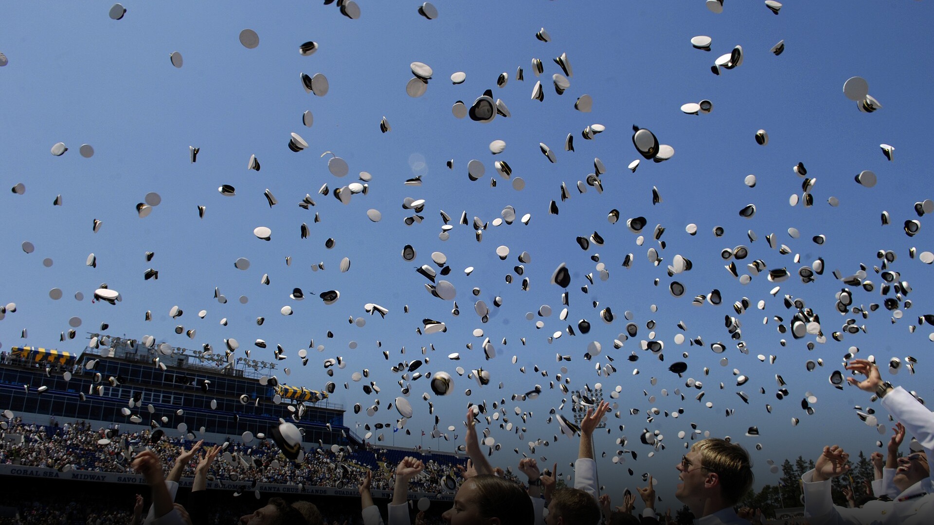 Graduates tossing their white caps into the air during a commencement ceremony.