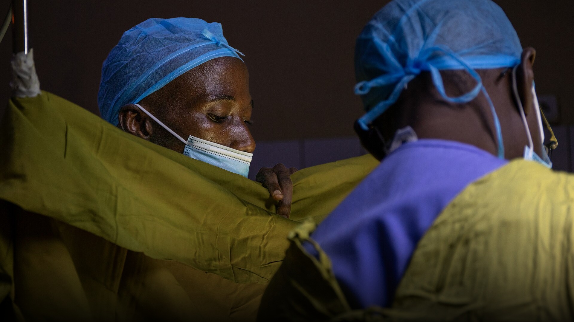 Surgeons and medical staff working together under bright lights in a hospital operating room.
