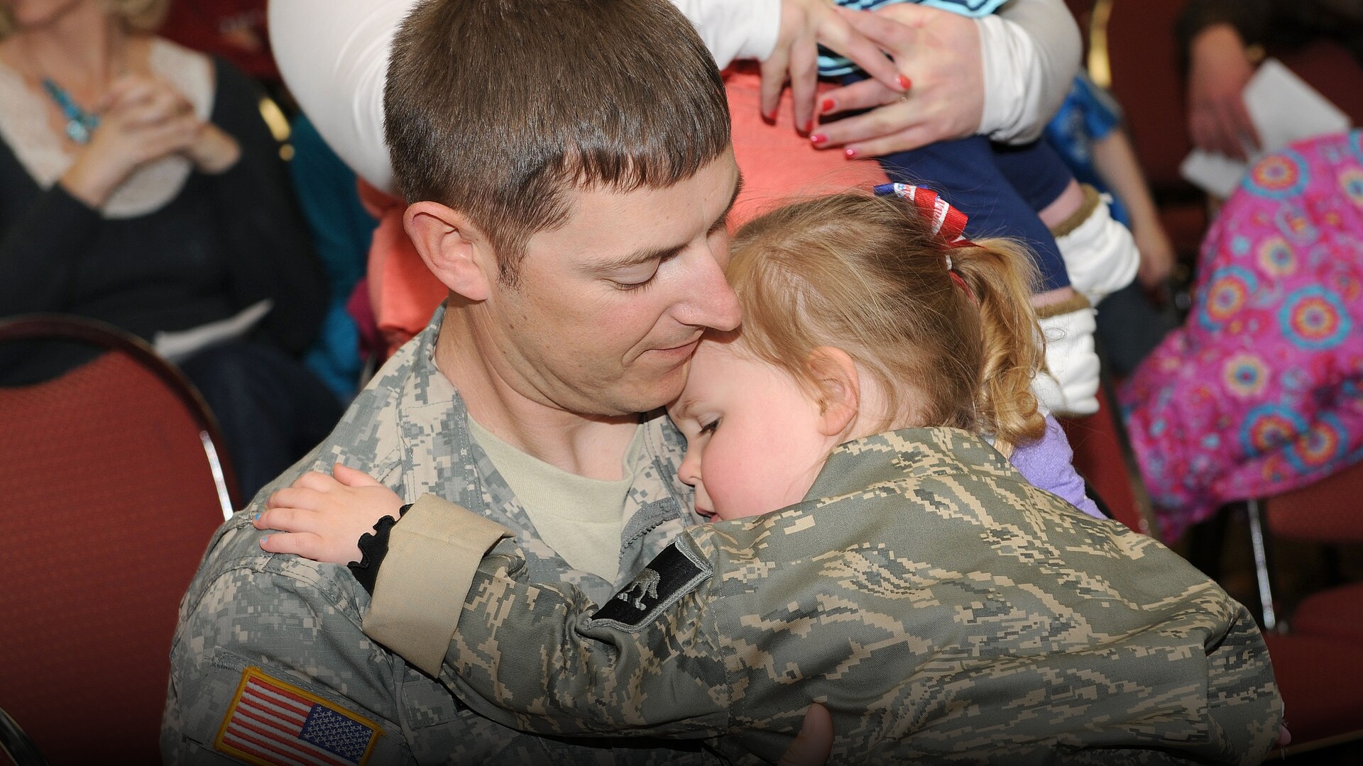 American parents and their young children embracing outdoors.