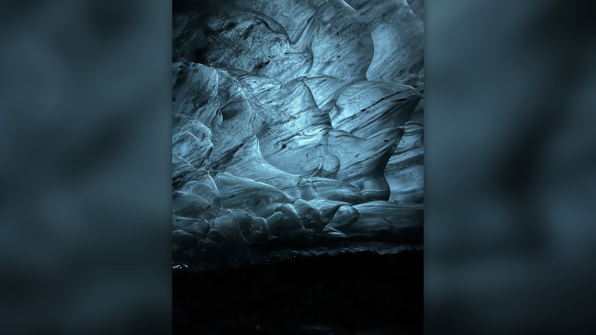 Translucent sapphire-blue ice walls inside a subglacial cave beneath Vatnajökull glacier in Iceland.
