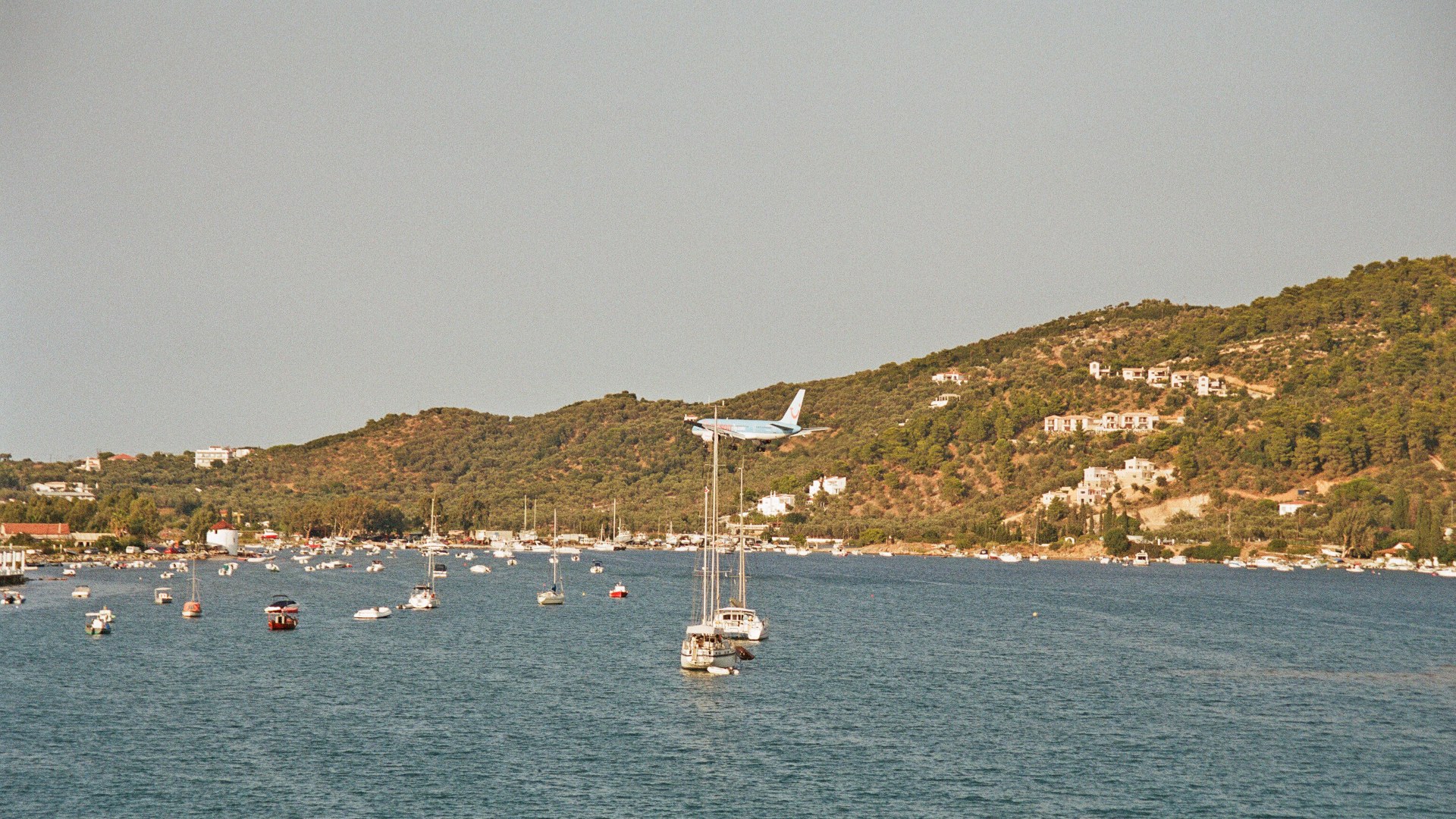 Passenger jet landing just feet above the coastal road and spectators at Skiathos Airport in Greece.