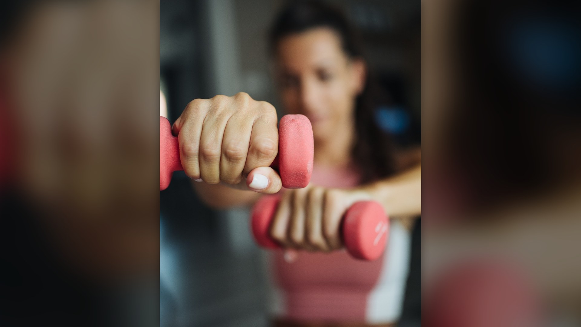 Woman performing dumbbell resistance training during an indoor workout session.