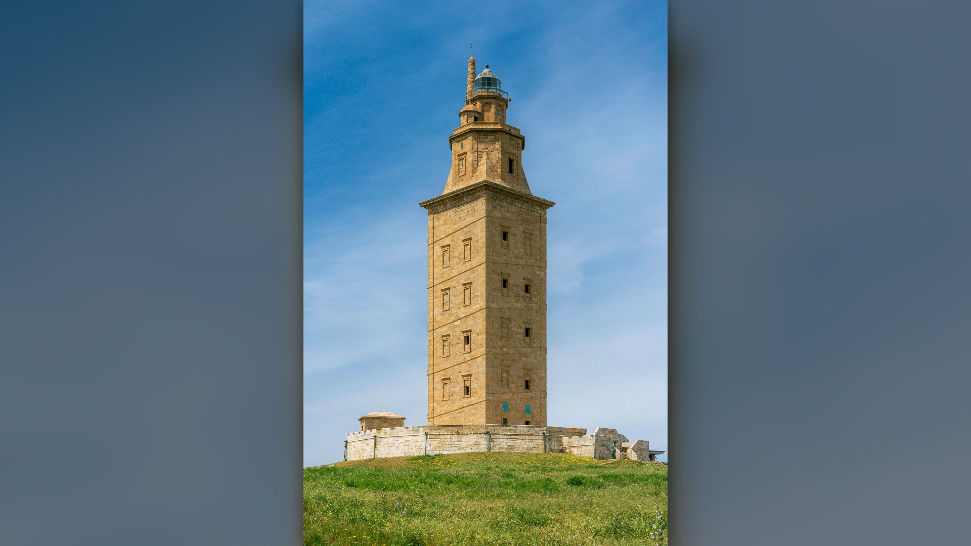 The ancient Roman lighthouse Tower of Hercules standing on a green coastal headland in A Coruña, Spain.