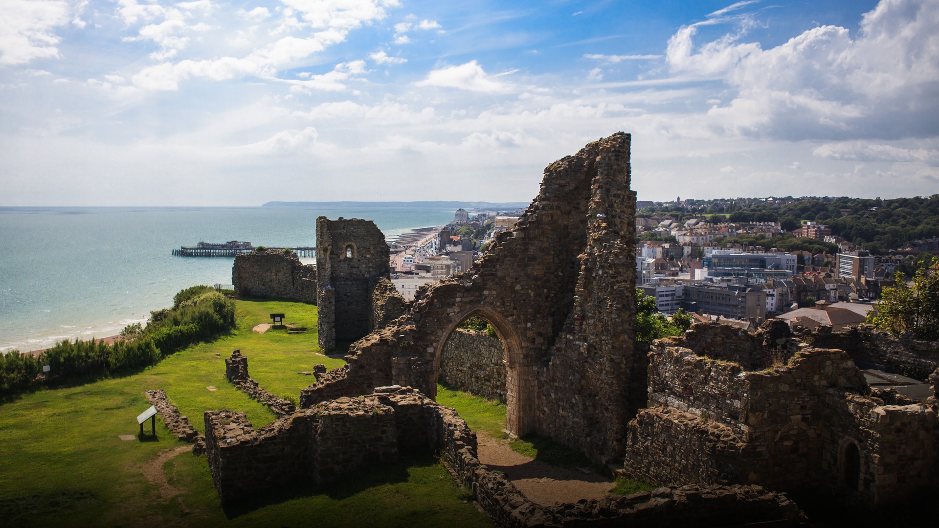 The ancient stone ruins of Norman Hastings Castle standing atop the cliffs overlooking the sea.