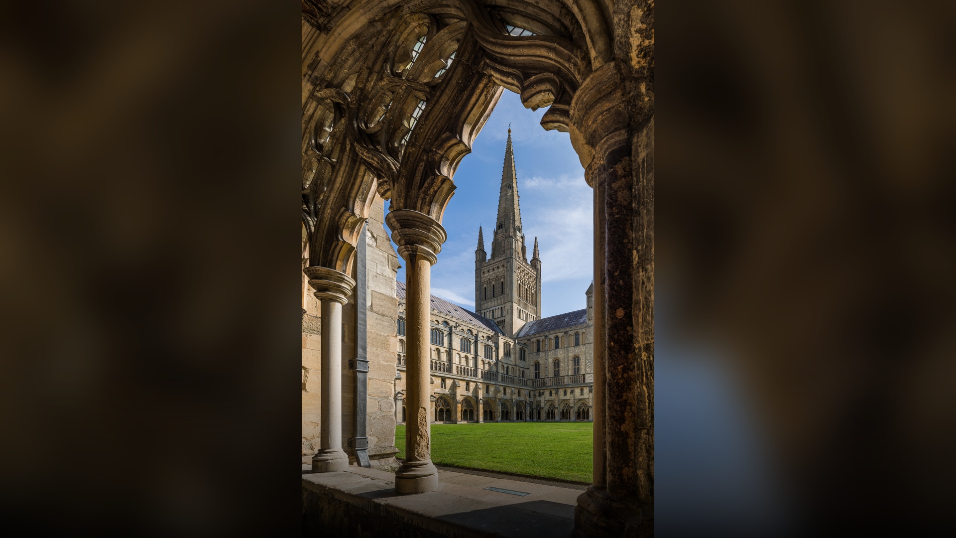 The majestic Norman stone spire and facade of Norwich Cathedral towering against the sky in Norwich.