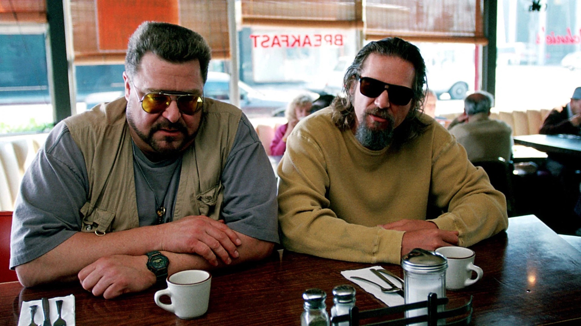 The Dude stands in his bathrobe holding a White Russian at the bowling alley in The Big Lebowski.