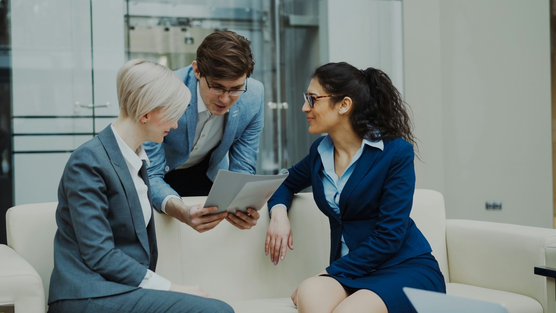 Three corporate executives in suits reviewing financial documents in a modern office.