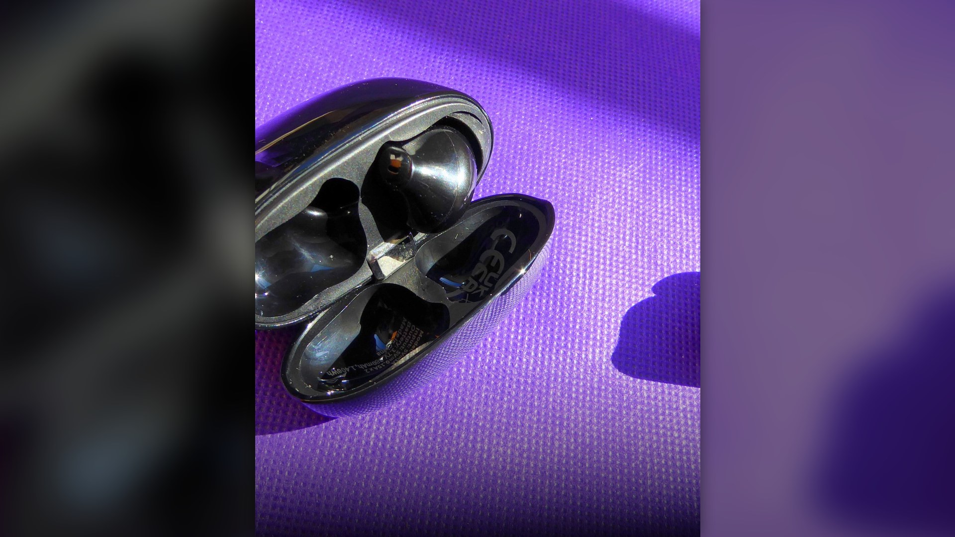 Close-up of black wireless in-ear earbuds and their charging case.