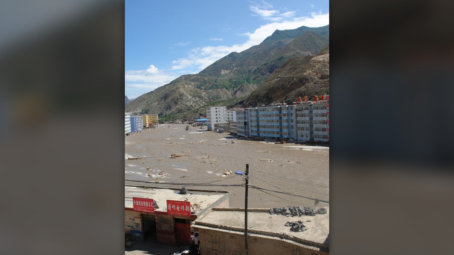 Collapsed loess mountainside and massive mudflow burying multi-story buildings in northwestern China.