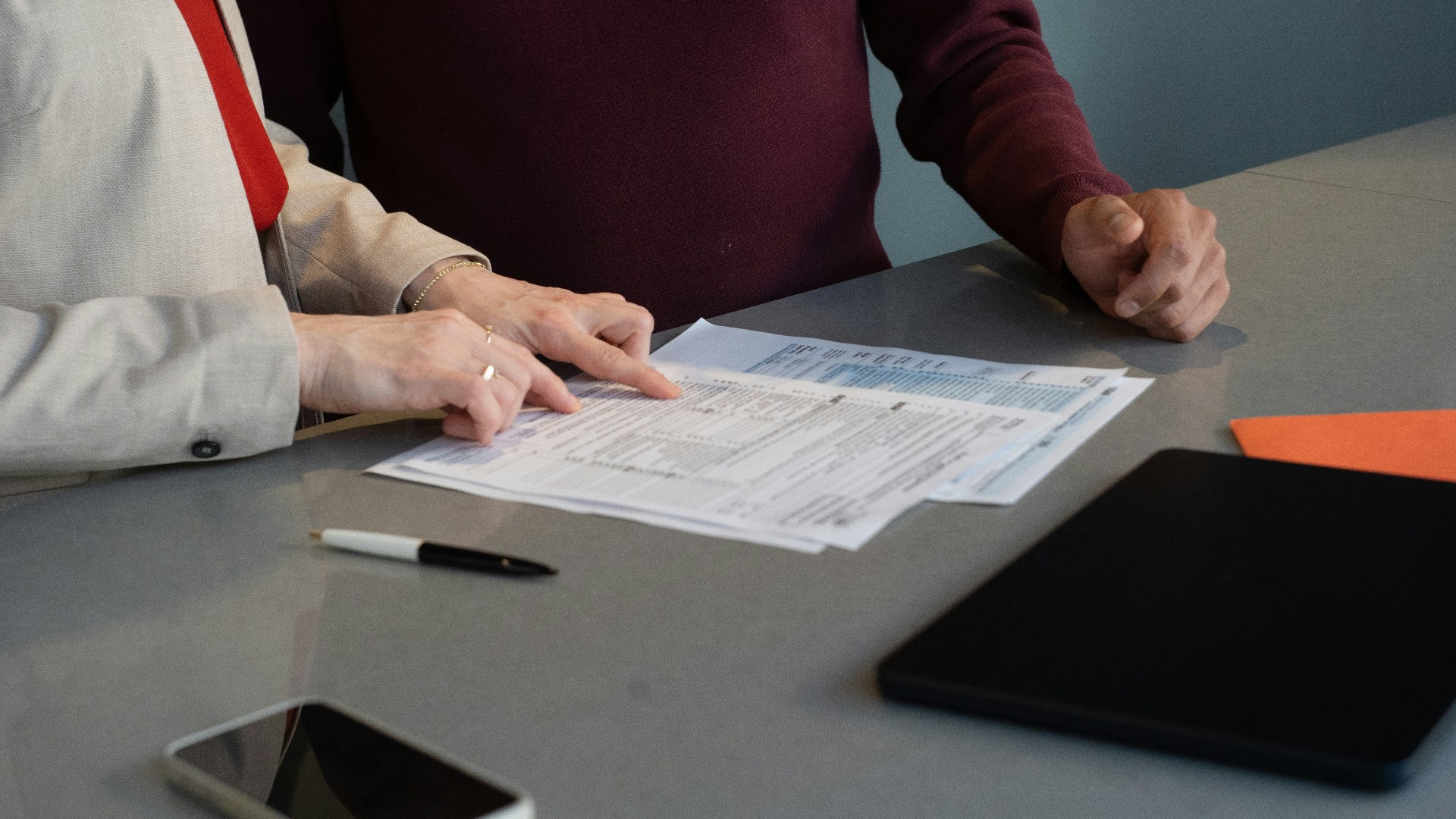 Two corporate professionals reviewing employment repayment documents at a conference table.