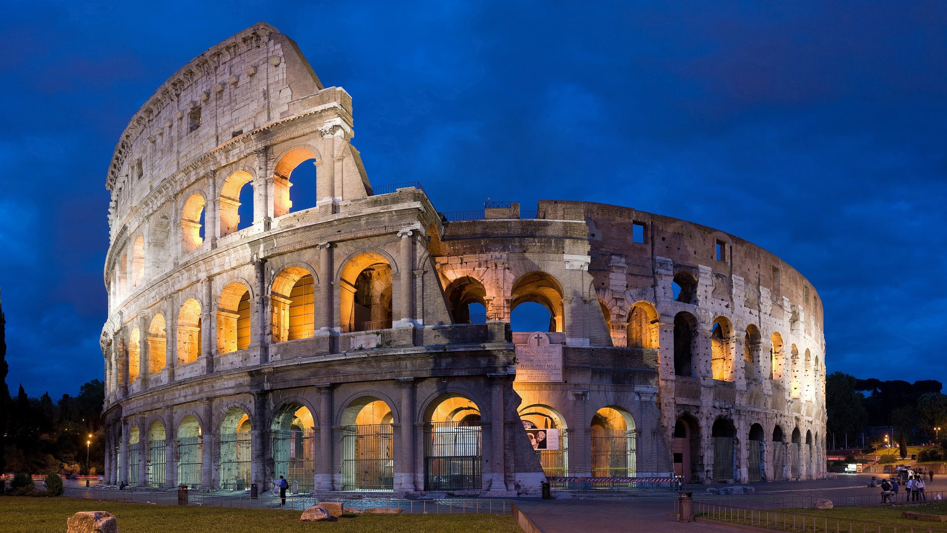 Exterior travertine arches of the ancient Roman Colosseum at golden hour.