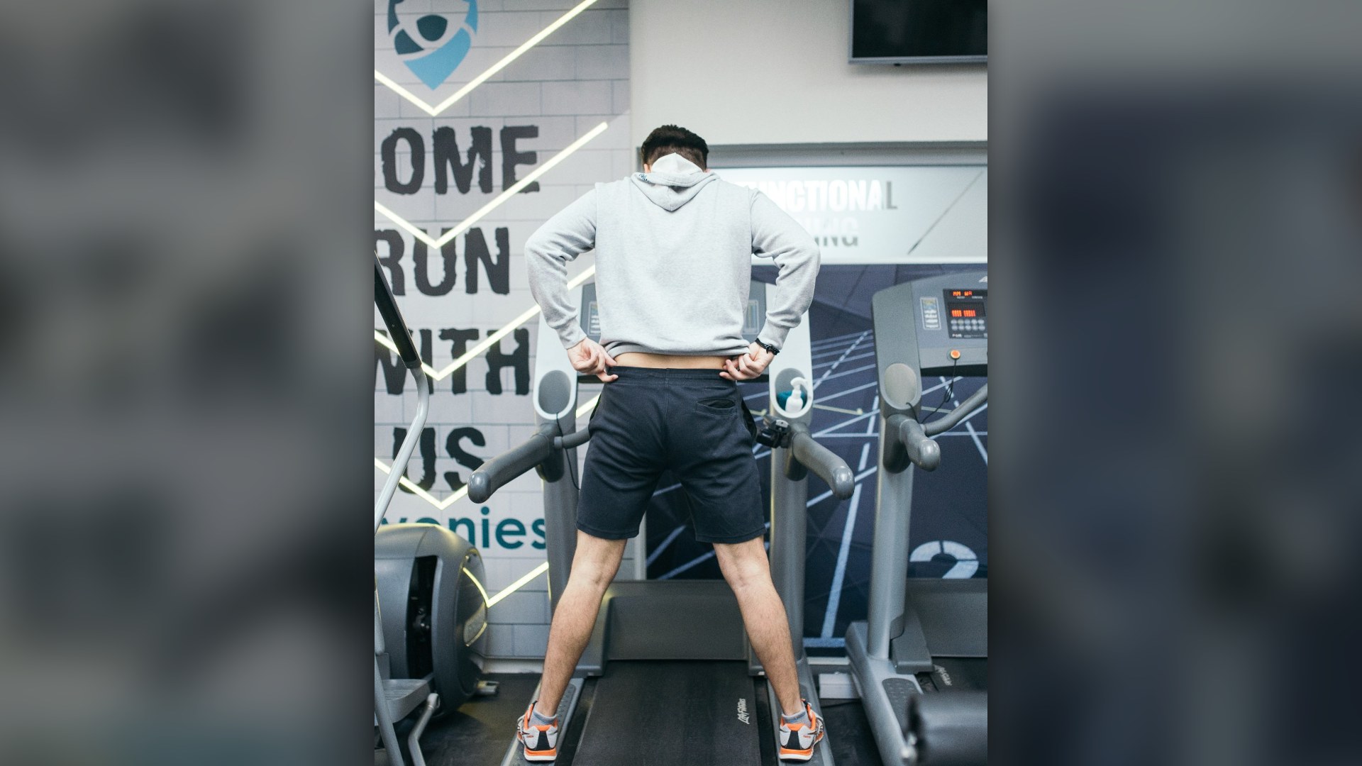 Young man running on treadmill during sports training in a gym.