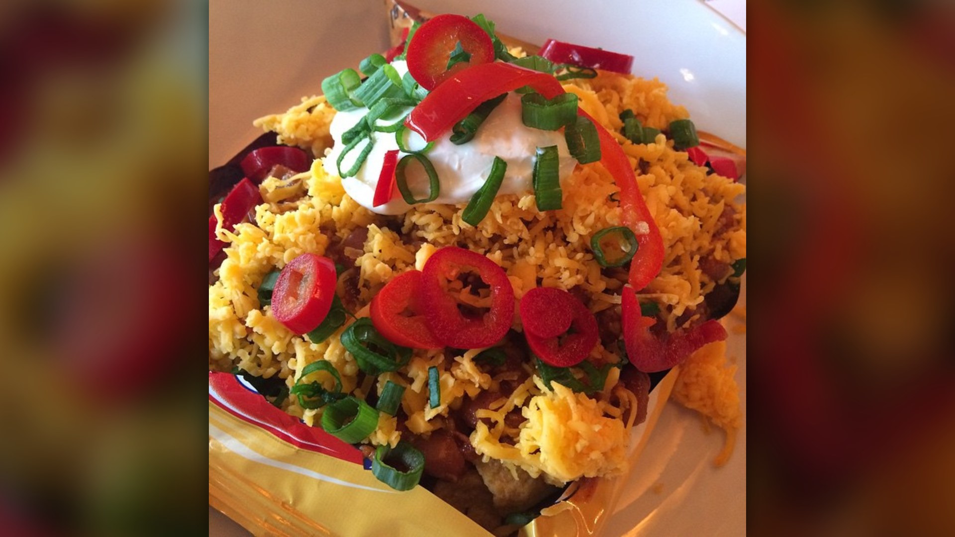 Frito pie served directly inside a split-open bag of Fritos corn chips with chili and cheese.
