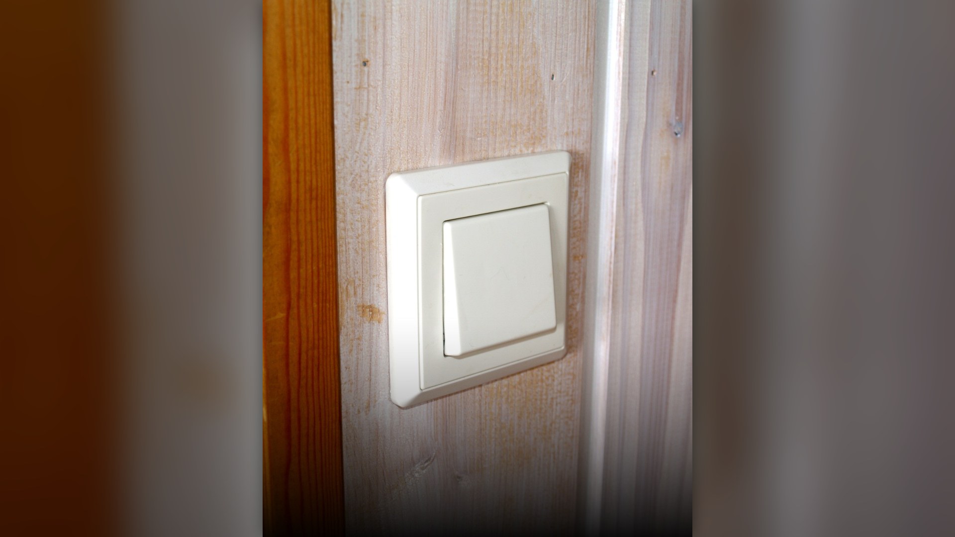 Close-up of a household white plastic wall light switch.