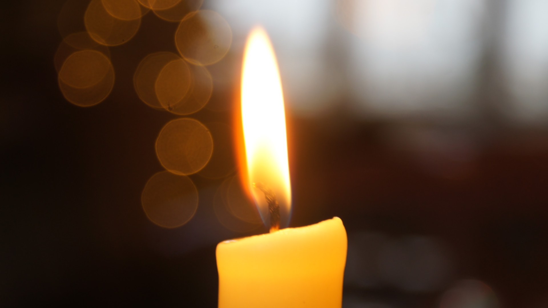 Close-up macro photograph of a burning candle wick and flame against a dark background.