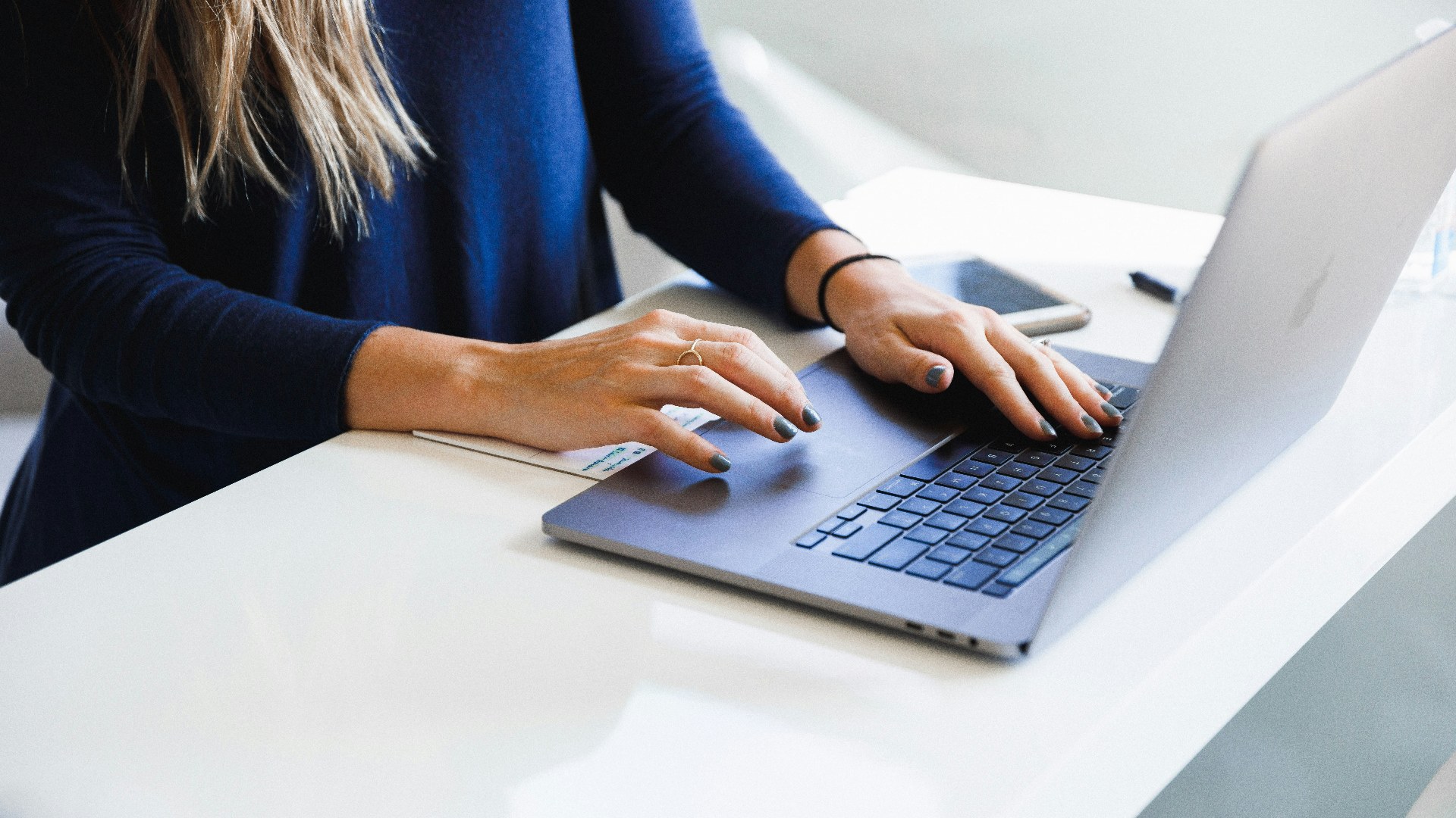Corporate employee working on a company MacBook Pro at an office desk.