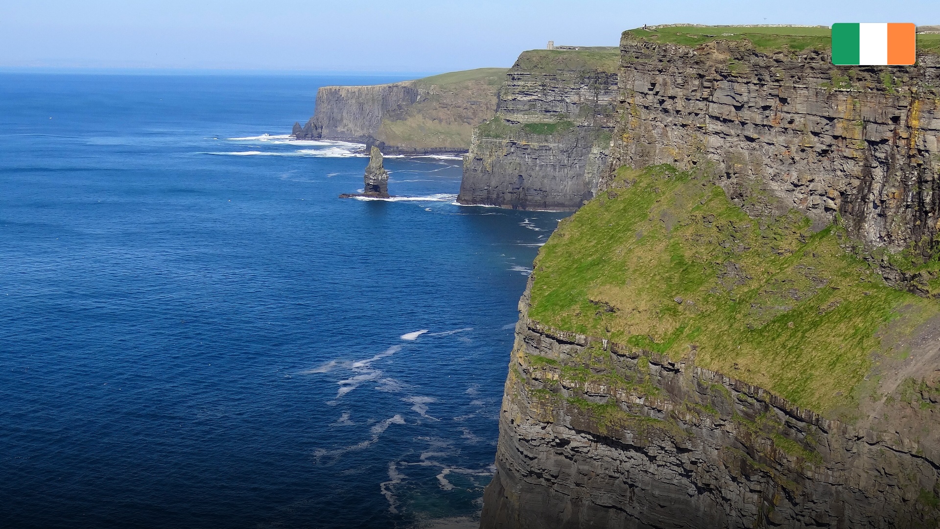 The dramatic, emerald green Cliffs of Moher dropping sheer into the crashing Atlantic waves.