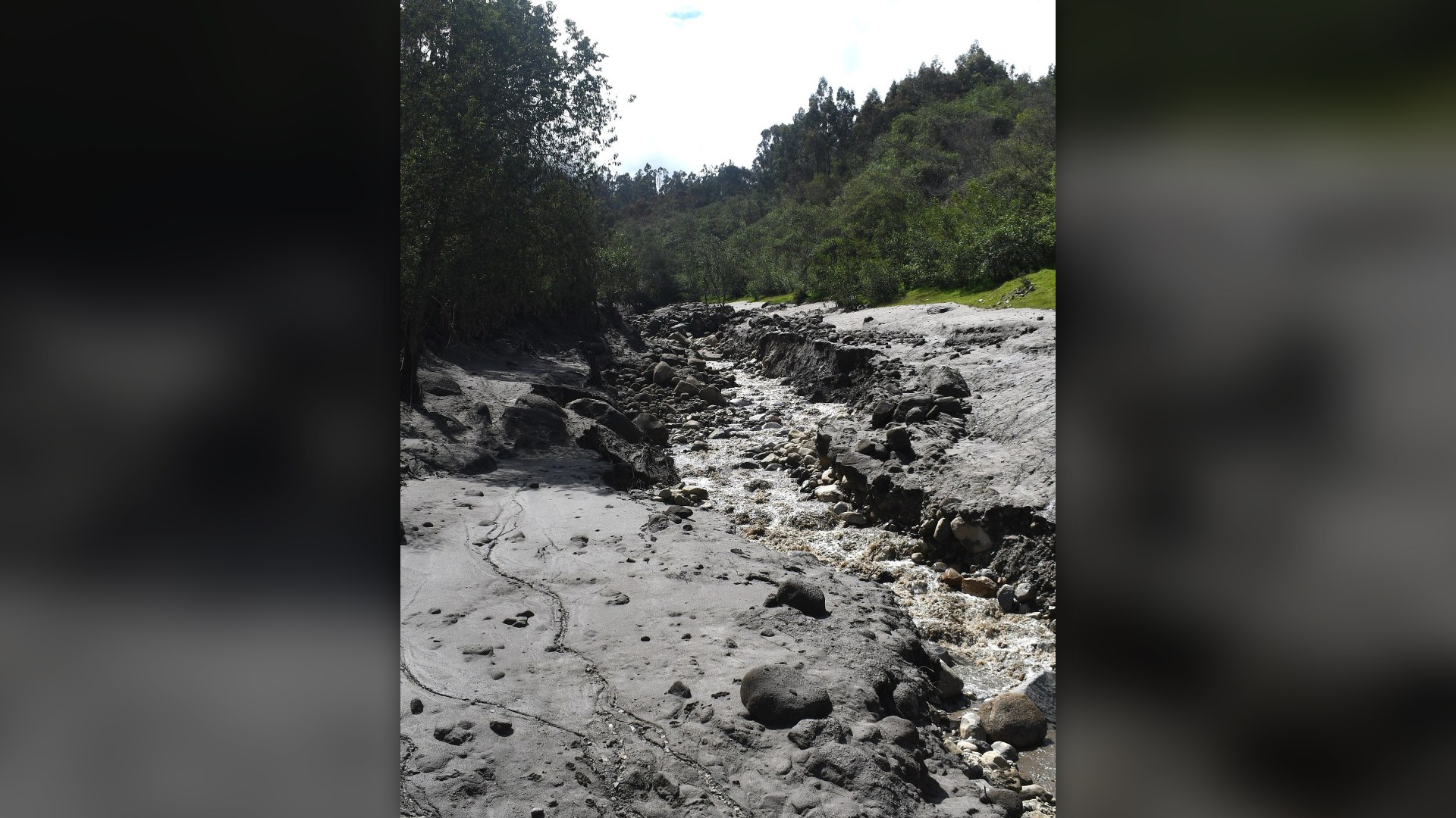 Glacial outburst debris flow channel filled with grey mud and boulders in the Llaca ravine at Huaraz, Peru.