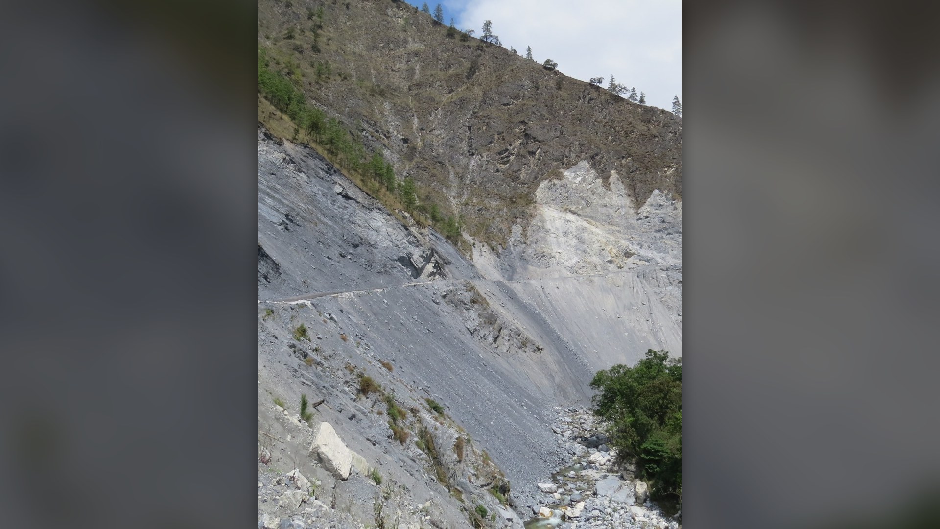 Enormous Himalayan mountainside landslide scar and rock debris slope collapsing into a river valley in India.