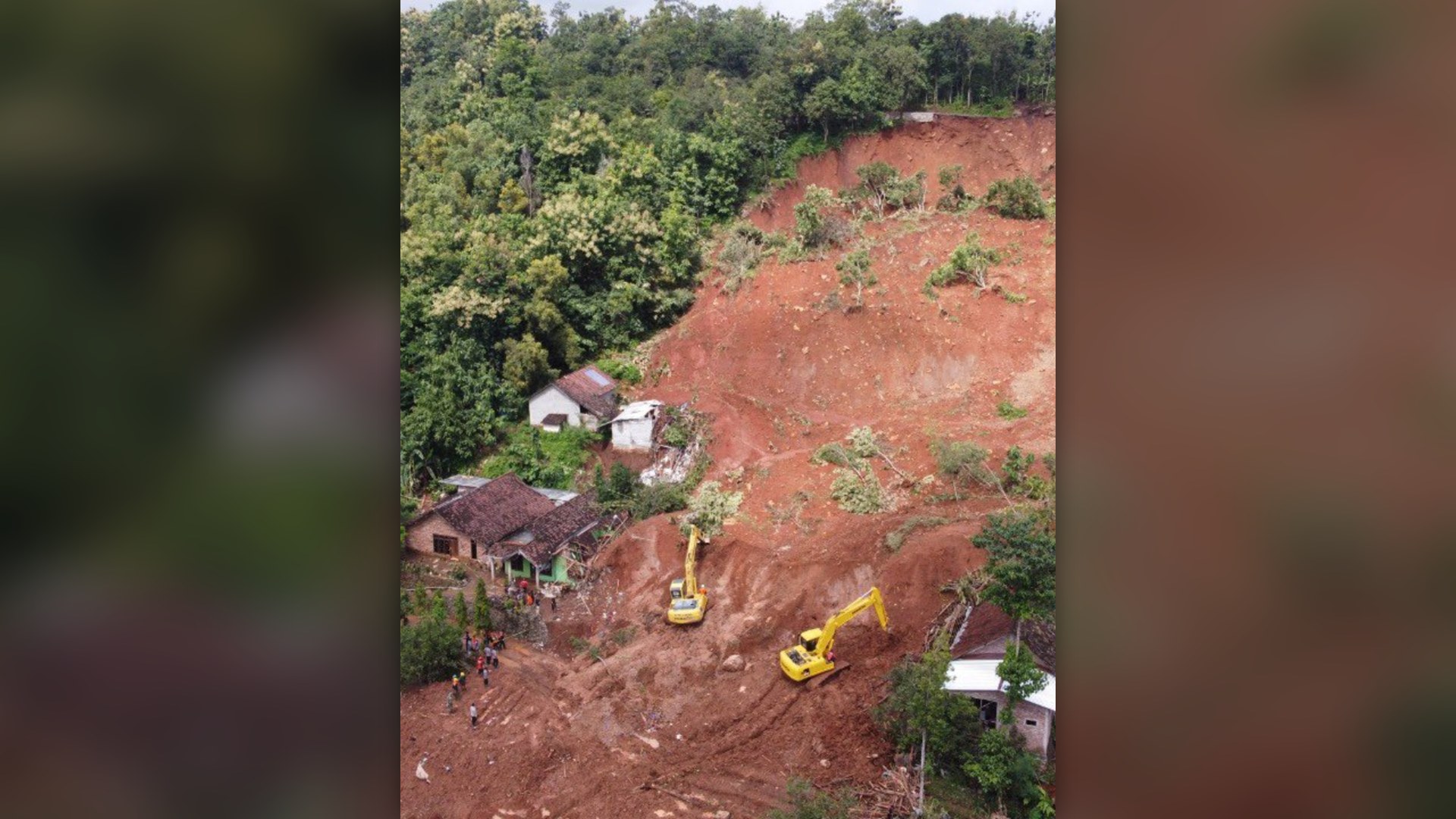 Massive red-earth mudslide and slope collapse burying village houses in East Java, Indonesia.