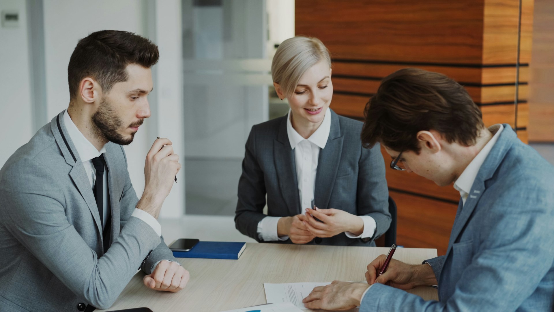 Business professionals signing a severance contract at a boardroom table.