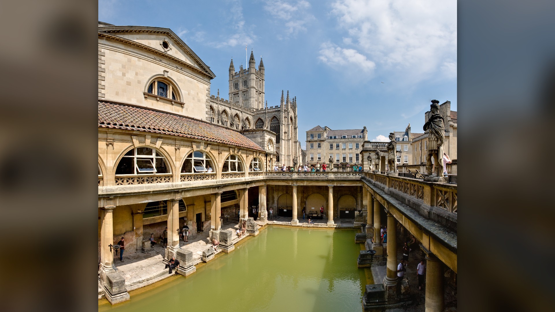 The steaming geothermal Great Bath surrounded by Roman stone colonnades in Bath, England.