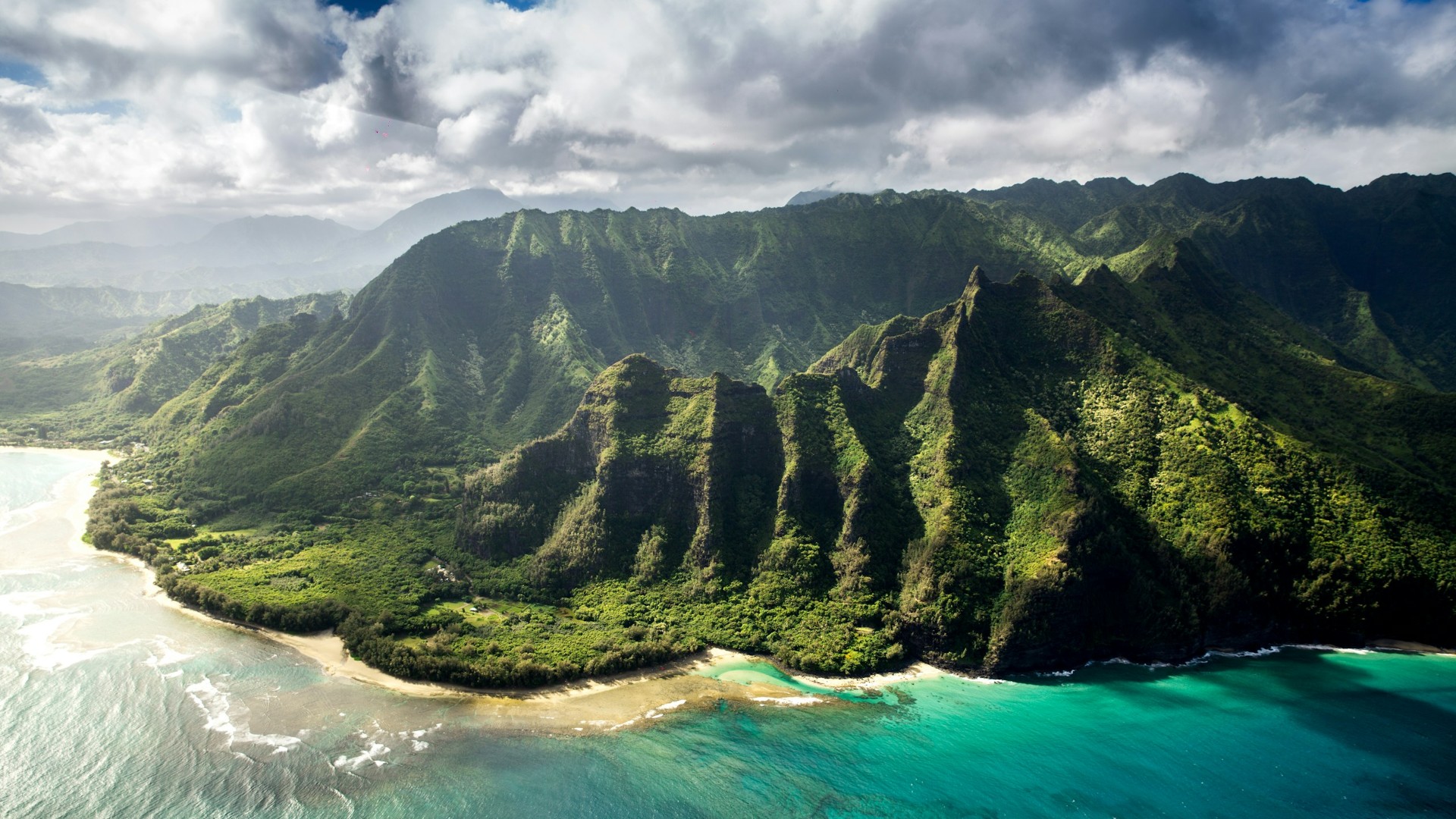 Emerald green volcanic cliffs and turquoise ocean waters along the Na Pali Coast of Kauai, Hawaii.