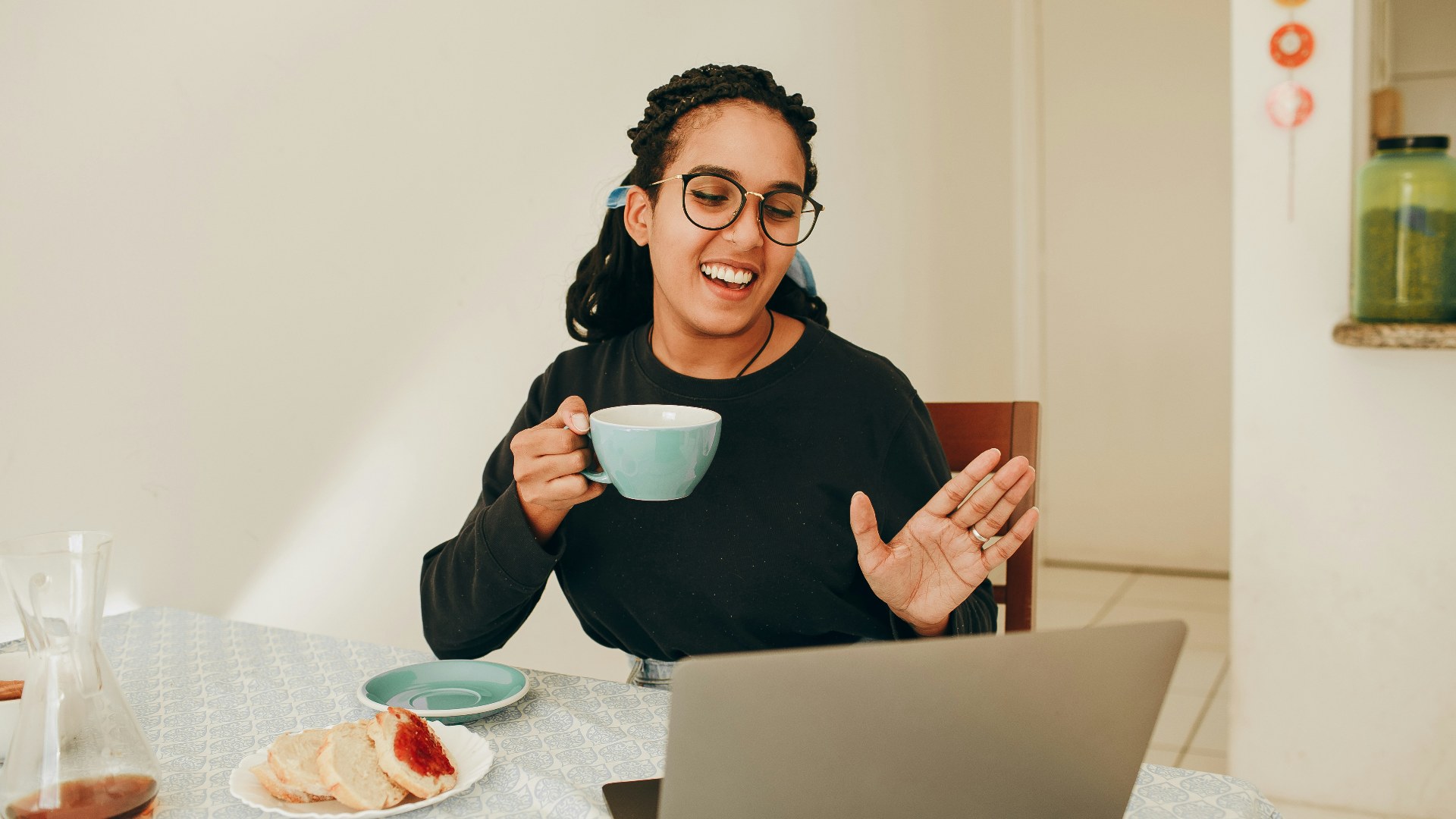 Woman speaking and waving during a remote video call on her laptop.