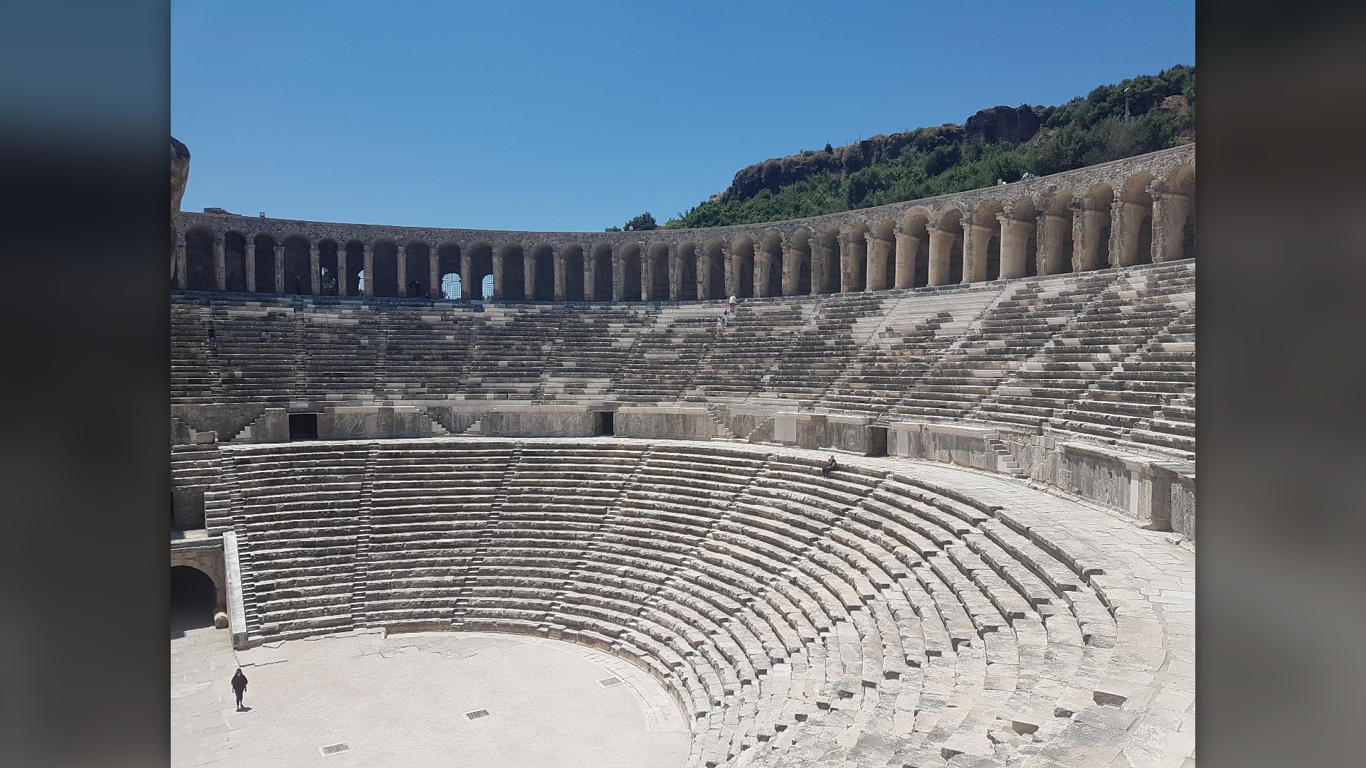 Steep stone seating tiers and complete Roman stage wall of the Aspendos Theatre in Turkey.