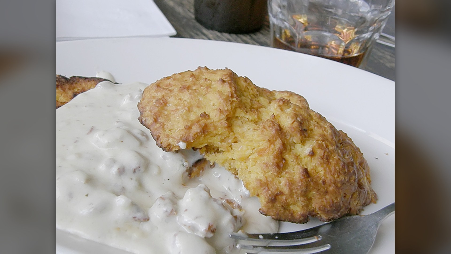A plate of flaky American buttermilk biscuits topped with white pork sausage gravy.
