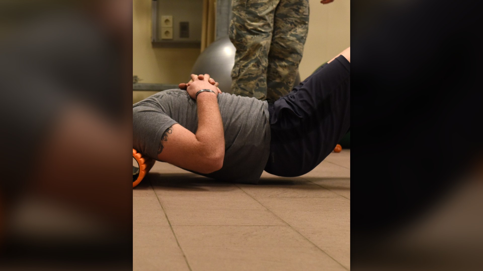 Military athlete using a high-density foam roller for myofascial recovery.