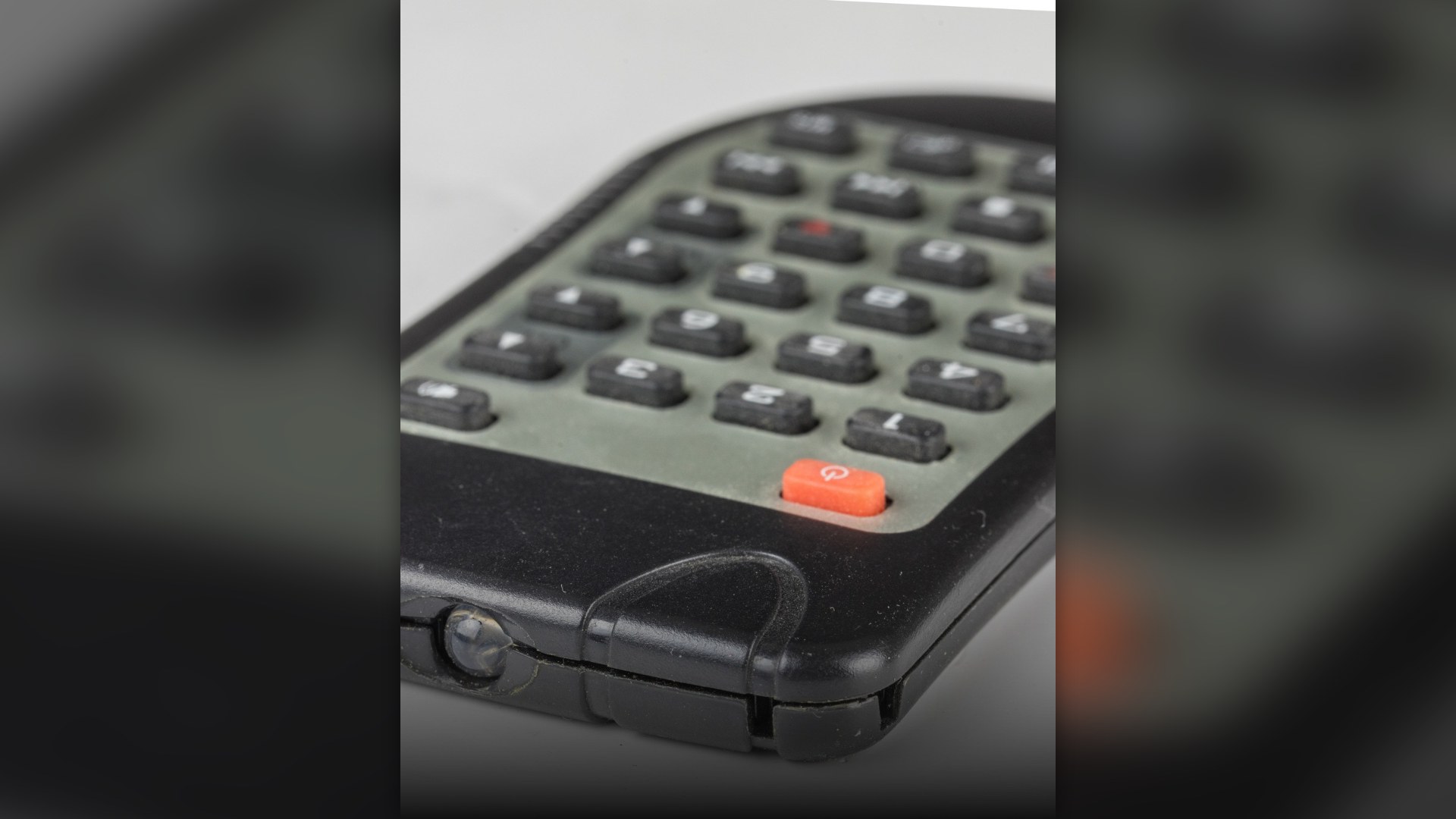 Close-up of a black television remote control and its rubber keypad buttons.