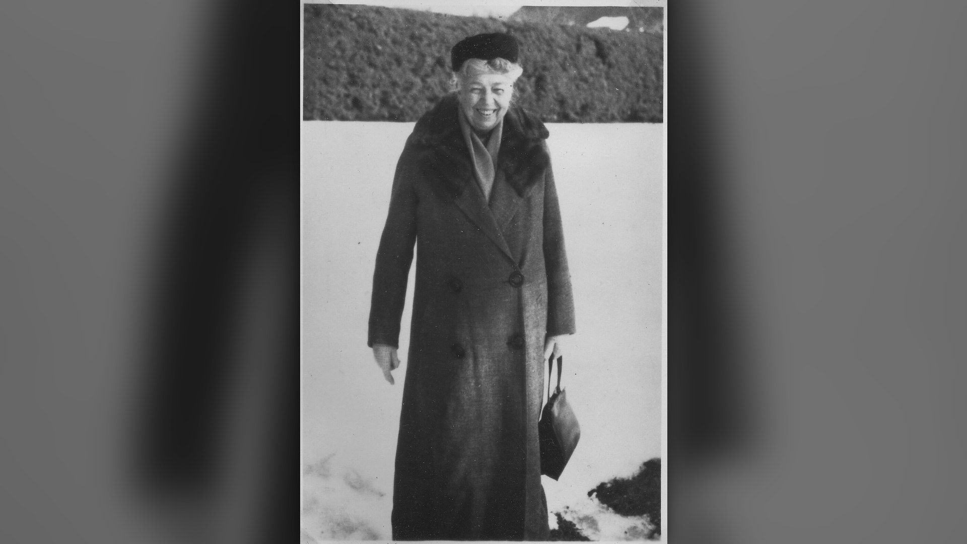 Eleanor Roosevelt seated writing at her desk.